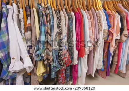 Variety of colorful womens clothing hanging on rail in fashion shop