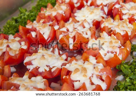 Closeup of cooked tomatoes with melted cheese on display at a hotel restaurant buffet