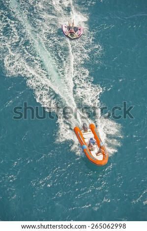 Inflatable toy being towed behind a speed boat during summer tropical sea holiday vacation