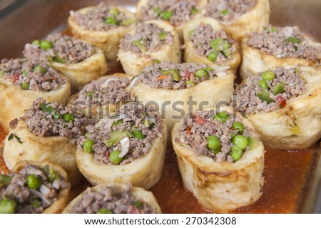 Closeup detail of roasted potatoes stuffed with minced meat on display at an oriental restaurant buffet