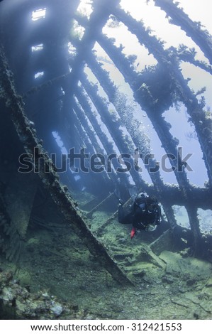 Scuba diver exploring inside a large underwater shipwreck