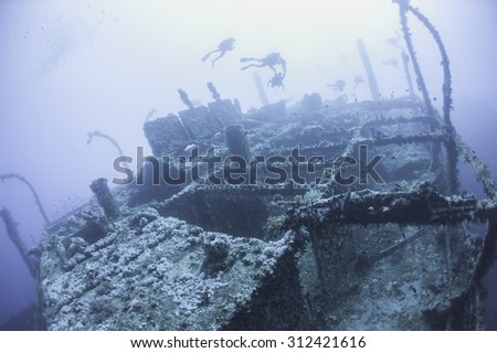 Technical scuba divers exploring a large deep underwater shipwreck