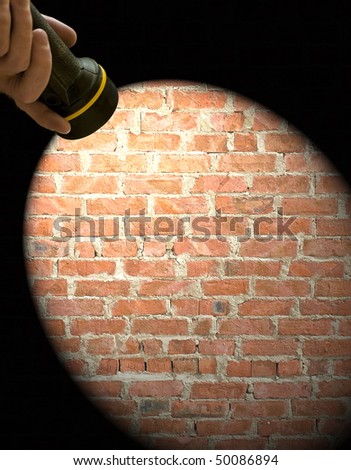 Hand held torch creating a light frame on a brick wall