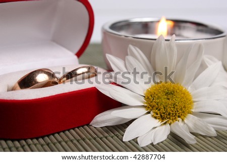 small box with weddings rings next to  candle and camomiles!