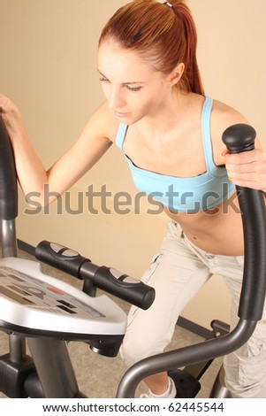 The young woman goes in for sports on training apparatus