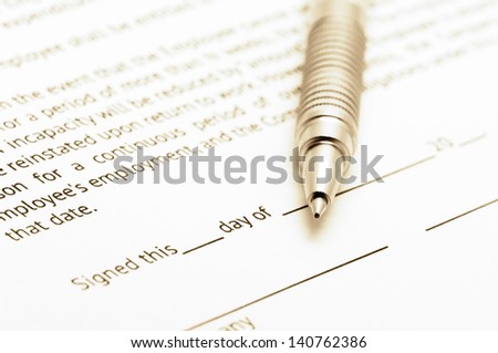 Close-up of silver pen on employment agreement. Selective focus on top of pen. Toned image.