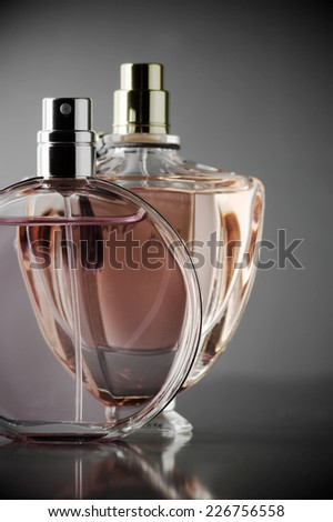 Two various bottles of woman perfume on dark gray background. Toned image.