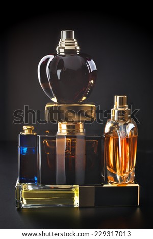 Various bottles of woman perfume on dark background.