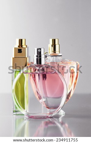 Three various bottles of woman perfume on gray background.