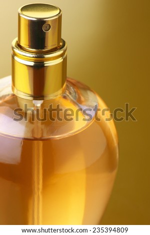 Bottle of woman perfume close-up on gold background.