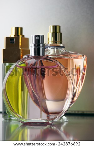 Three various bottles of woman perfume on gray background.
