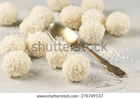 Coconut candies and spoon on wooden shabby background. Shallow DOF, focus on foreground.