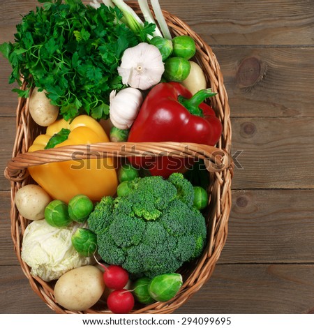 Assorted vegetables in basket on rustic wooden background. Top view point.