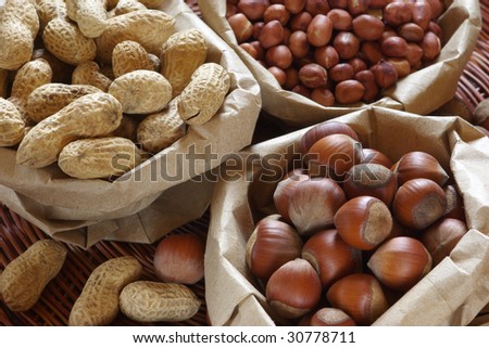 Hazelnuts, raw and roasted peanuts in paper bags.