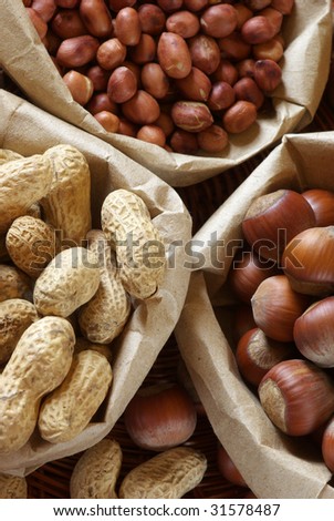 Hazelnuts, raw and roasted peanuts in paper bags.