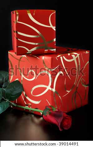 Two ornamented red gifts and red rose on black background.