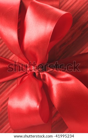 Close-up of red satin bow on red striped wrapping paper.