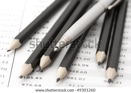 Group of black pencils and silver pen on paper tables with numbers.
