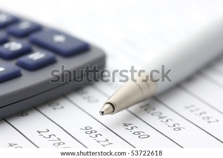 Close-up of silver pen and calculator on paper table numbers.