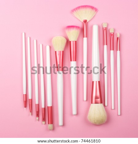 Set of white-pink make-up brushes on pink background.