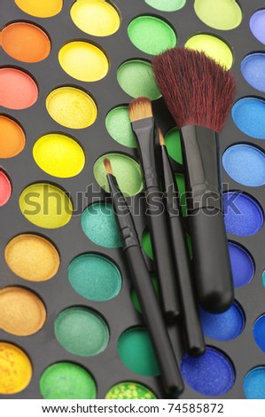 Set of make-up brushes on colorful eye shadows palette.