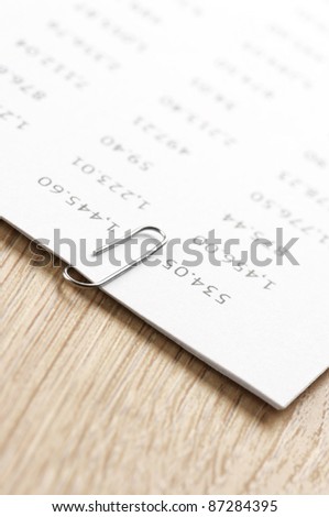 Close-up of pages fastened with paper clip on wooden desk.