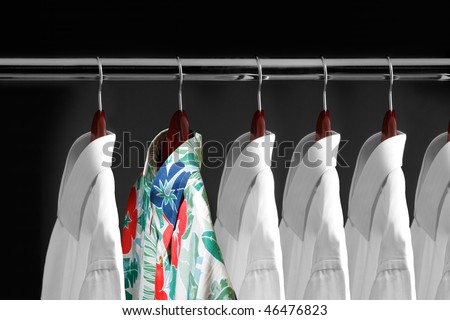 Tropical shirt between white shirts hanging inside a closet