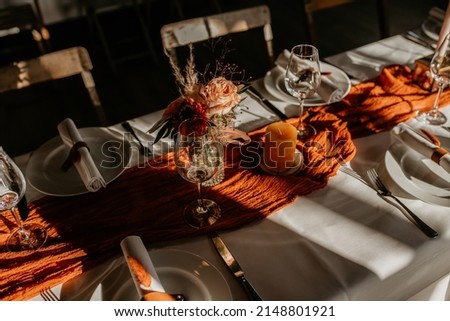 Table setting for an event or wedding boho chique. Luxury and elegant in orange with plates and wineglasses Foto stock © 