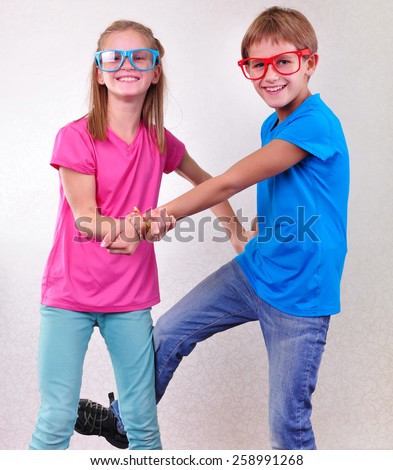 portrait of playful brother and sister twins with sunglasses fighting and having fun