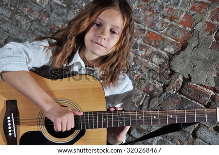 Pretty young teen girl playing acoustic guitar music in the street. Youth music culture concept.