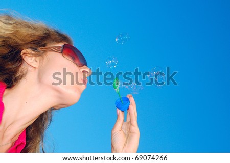 beautiful young woman blowing bubbles in the sky