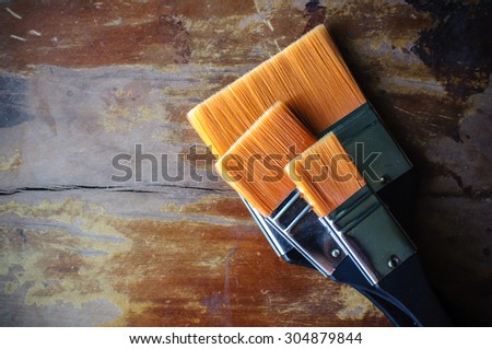 Paint brush or paintbrush resting on the wooden floor.