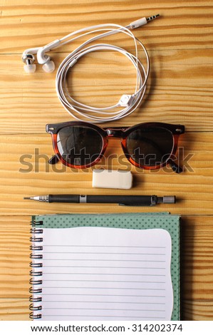 Office equipment such as notebook open highlighters , pencils , sticky notes , glasses , headphones, and other inanimate desk .