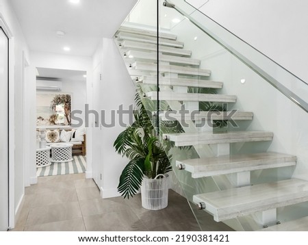 Staircase with glass balustrade, plant and view through to lounge room. Imagine de stoc © 