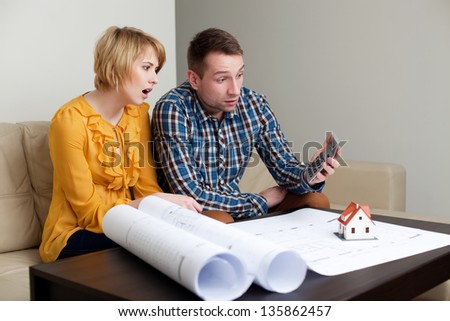 Shocked couple calculating the price of a home