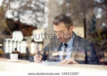 Businessman sitting in coffee shop, signing contract