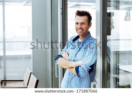 Young smiling adult standing next to a sliding glass door