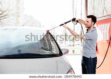 Young man cleaning his car with a jet sprayer