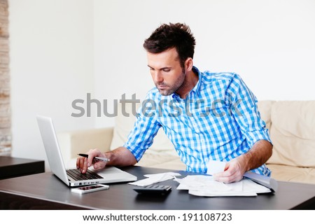 Young man paying bills with his laptop