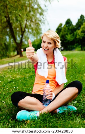 Photo of a satisfied woman runner sitting on the grass after a park run