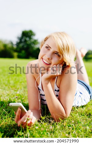 Young happy woman listening to music and enjoying her day in the green