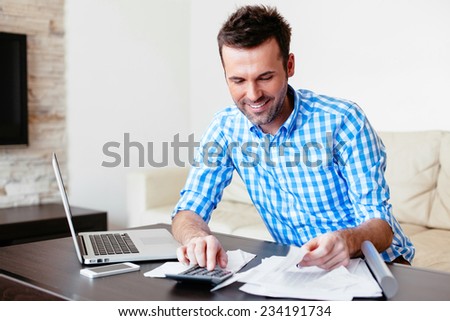 Smiling young man analyzing his expenses and paying online