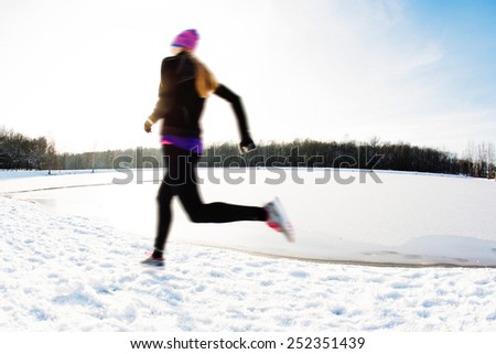 Blurred picture of young woman running at winter