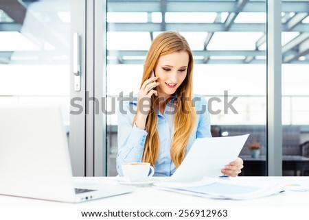 Pretty secretary sitting at a desk and talking on a mobile