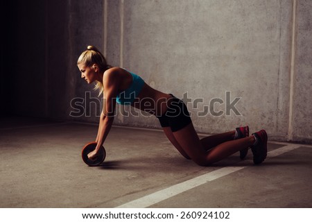 Young woman training with ab wheel