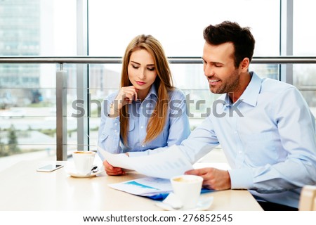 Two successful sales managers looking at sale figures in an office