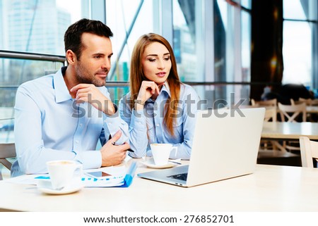 Business team of two in an office looking at some data on a laptop