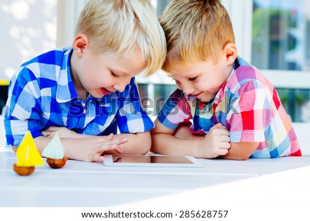 Happy twins playing together on digital tablet