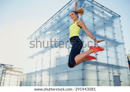 Happy young female runner jumping high  after running race