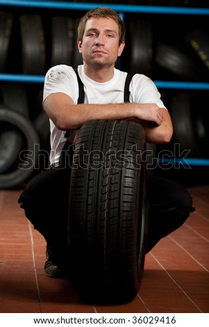 Mechanic crouching with tire in tire service
